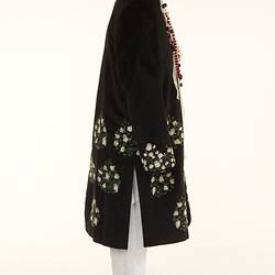 Black coat with white floral detailed pattern over white chinos pants.