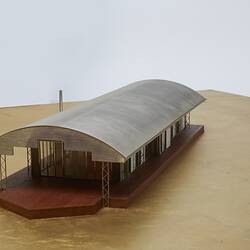 Model of a house with an arched roof, corrugated iron and wide expanses of glass.