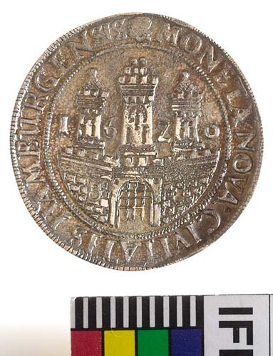 Medal with raised scene, view of city gates with three towers behind. Framed by beaded border and raised text