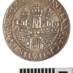 Medal with raised scene, view of city gates with three towers behind. Framed by beaded border and raised text