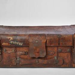 Worn brown leather suitcase with buckles. Fragile label on front.