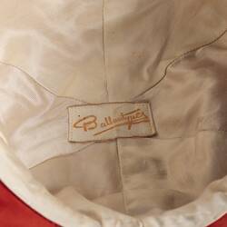White fabric lining inside of jockey cap. White label, yellow lettering.