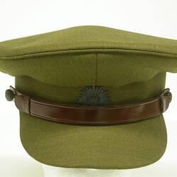 Green khaki cap with brown leather hat band and broach on front centre.