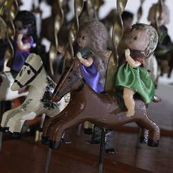 Detail of figures on horses on carousel model.