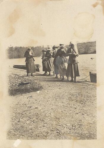 Group of woman standing by water.
