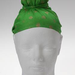 Topknotted green headscarf with decorative gold stamp design.