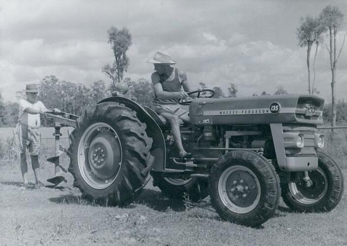 Man driving a tractor with post hold digger.