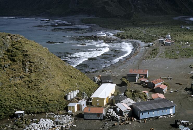 Group of buildings with sea and hill.