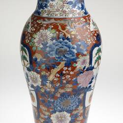 Ornate colourful vase, slightly tapered body with a small lip. Off-white base with peonies, cherry blossoms, chrysanthemums, fans and butterflies.