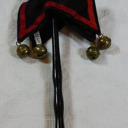 Mock sceptre with small jester's head made of cream cloth mounted on black wooden stick.