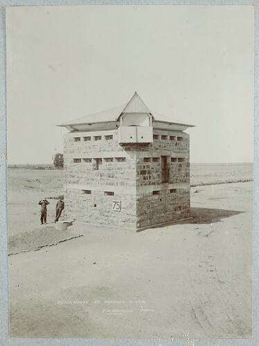 Two man standing next stone building.