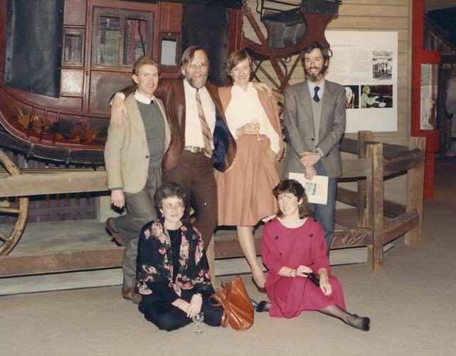 Group posed with coach in museum exhibition.