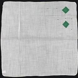 Unfolded handkerchief with green embroidered diamonds.