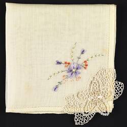 Folded handkerchief with embroidered and crocheted flowers.