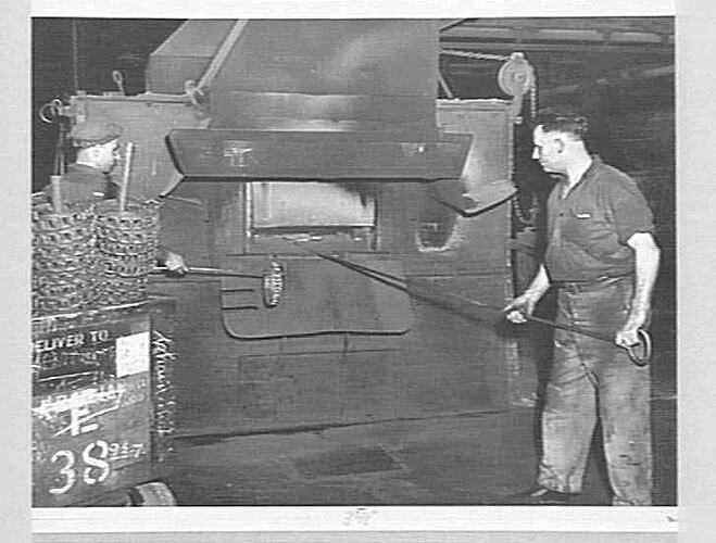 Two men working with a furnace.