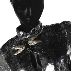 Silver dress. Detail high collar with gold/black dragonfly brooch above central split.