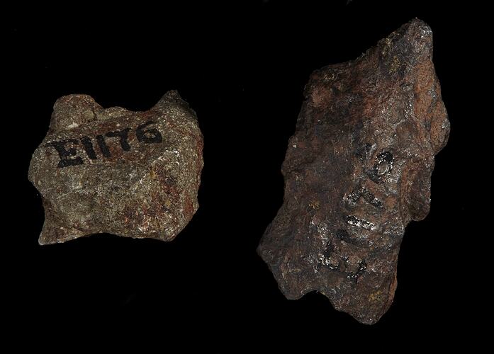 Two pieces of brown-orange rock, one with black numbers written on it.