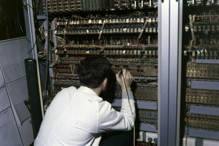 Worker crouching down in front of control panel.