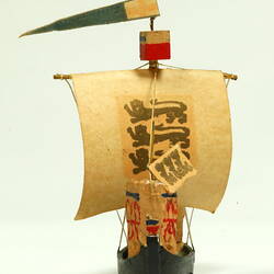 Front view of ship with black hull and painted sail.