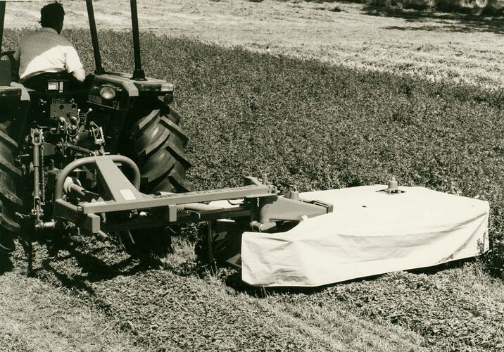 Rear view of drum mower attached to back of tractor.
