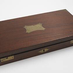 Wooden case with brass handle in lid, hinges and corners.