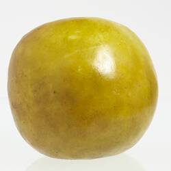 Wax model of an apple painted yellow.