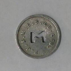 Round coin with M cut out of centre.