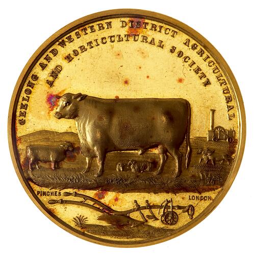 Round gold medal with cattle, sheep, harnessed horses, portable engine in background. Text along top edge.