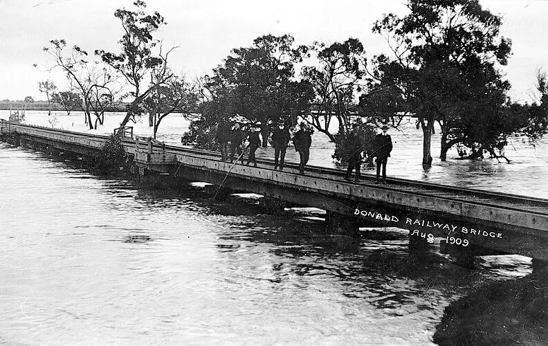 People on rail bridge amid floodwaters, Donald, August 1909.