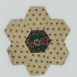 Cream with spots hexagonal coloured fabric patches that are stitched together.Blue floral centre.