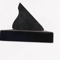 Side view of black wooden label and its support.