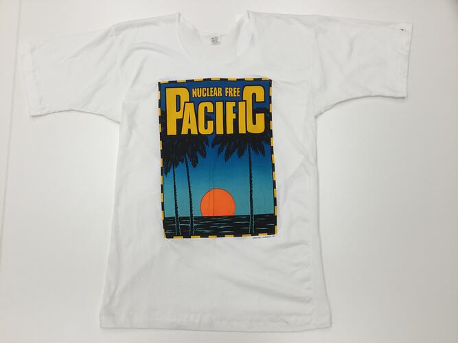 White t-shirt with sun over the sea with palm trees. Yellow text above.