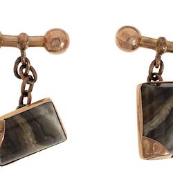Rectangular rose gold cufflinks, each with a striped grey stone. Set in rose gold with chain attached to dumbbell-shaped toggle. Initials in gold-tipped corner.