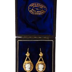 Gold mounted cameo earrings with a classical woman's profile with cloth draped over the shoulder. In dark velvet lined box.