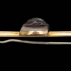 Profile of gold bar brooch with centrally placed, rectangular cameo. Made of dark brown hardstone the cameo features a bearded male bust facing left with lighter brown background.