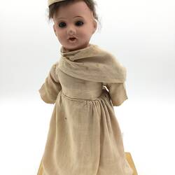 A doll dressed as a Benedictine Monk in a pale brown cassock and cap