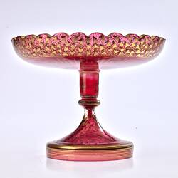 Red glass base/stand of epergne. Shaped like one piece plate on stand. Gilded decoration.