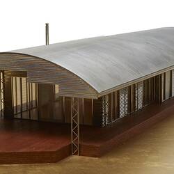 Model of a house with an arched roof, corrugated iron and wide expanses of glass.