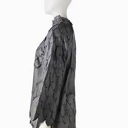 Short shift-style dress made from irregular pieces of pewter grey leather to resemble reptilian scales. Left profile.