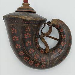 Volute shaped wood flask covered with red patterned papier mache. Wide sealed opening with wooden stopper curls to thin spout. Has strap.