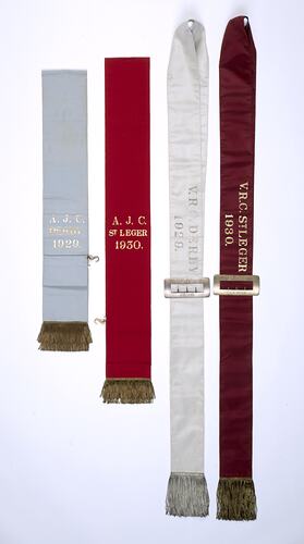 Four ribbon sashes with fringe and lettering.