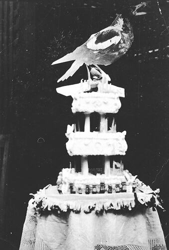 Multi-tiered cake with wooden magpie on top.
