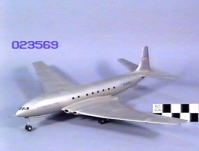 Silver model aeroplane, four wheels beneath each wing and two front wheels. British flag painted on tail.