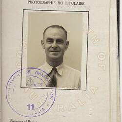 White passport page with photo of man, black printed text and blue handwritten text.