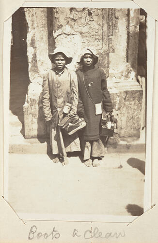Two children standing by a stone structure.