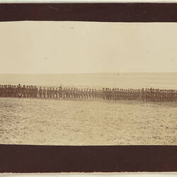 Rows of servicemen standing in formation in field.
