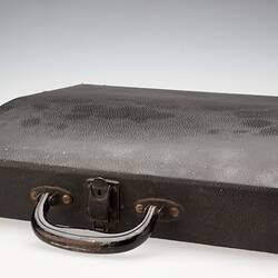 Brown leather case, closed, with worn handle.