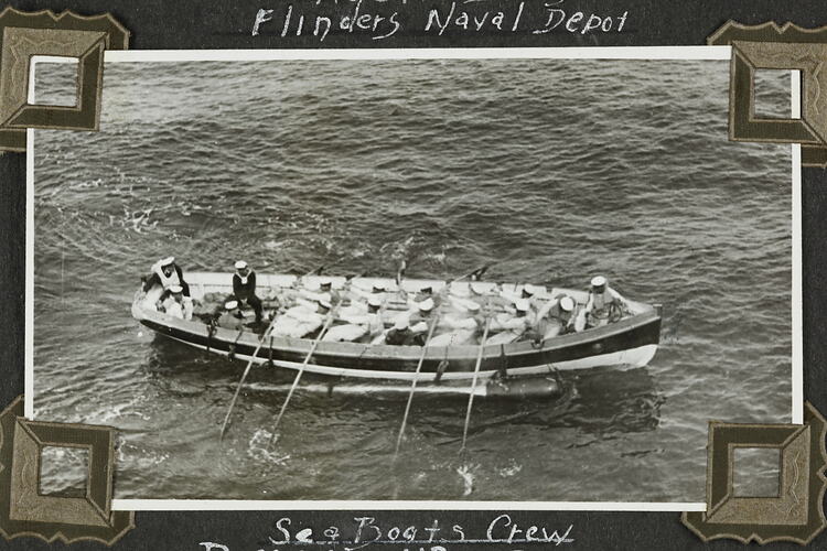 Row boat with crew alongside a long metal object in water.