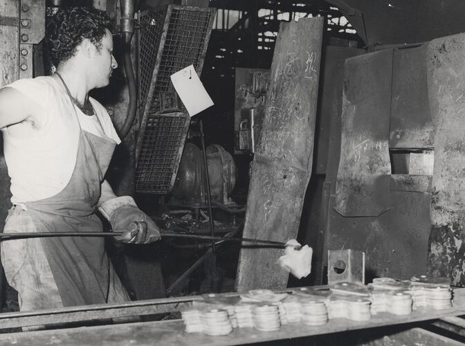 A man is loading blank tine points into a furnace.