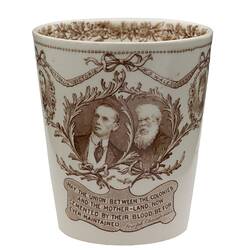 Cream earthenware beaker with sepia floral patterning. Two cameos of men and text below.
